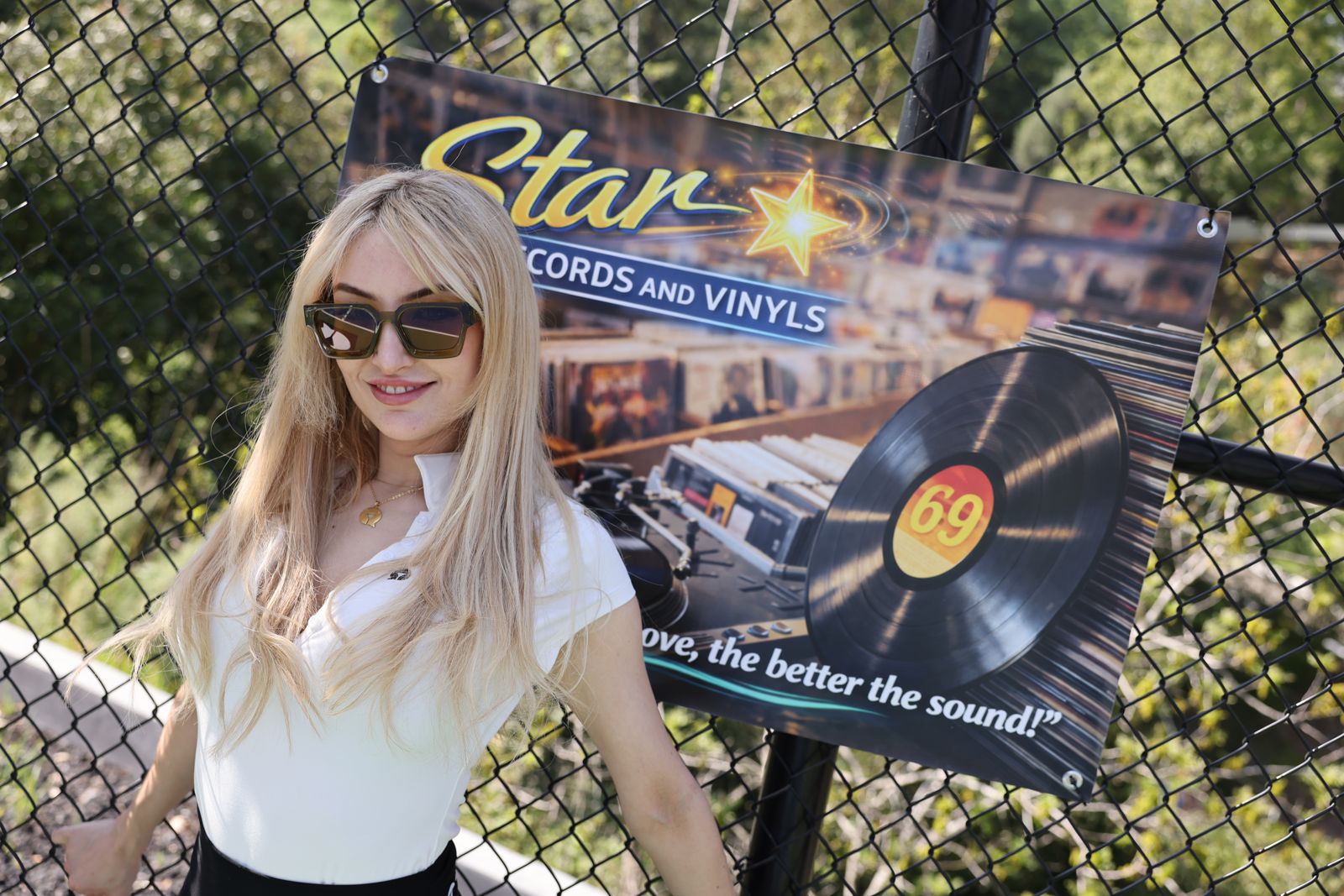 A cast member poses with her parody sponsor banner at the SC House pickleball tournament